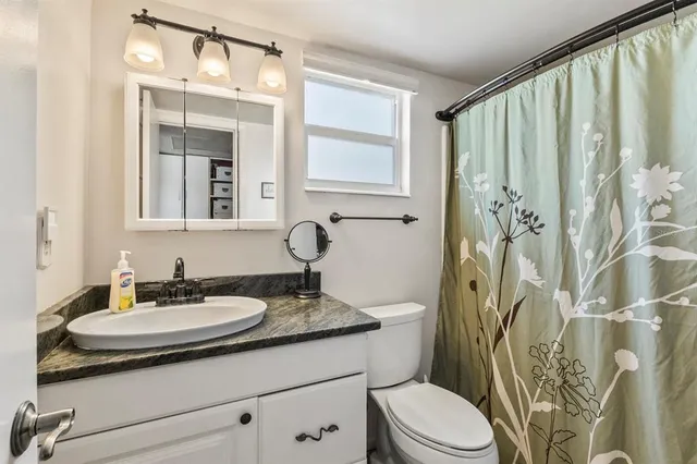 a bathroom with a granite countertop sink a toilet and a mirror