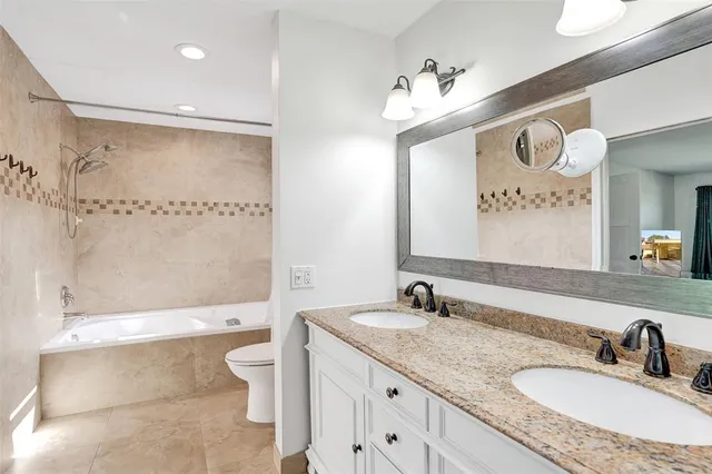 a bathroom with a granite countertop sink mirror vanity and toilet