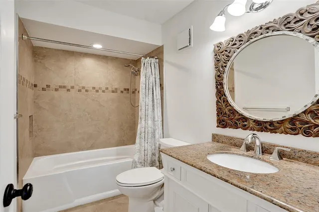 a bathroom with a granite countertop sink mirror toilet and bathtub