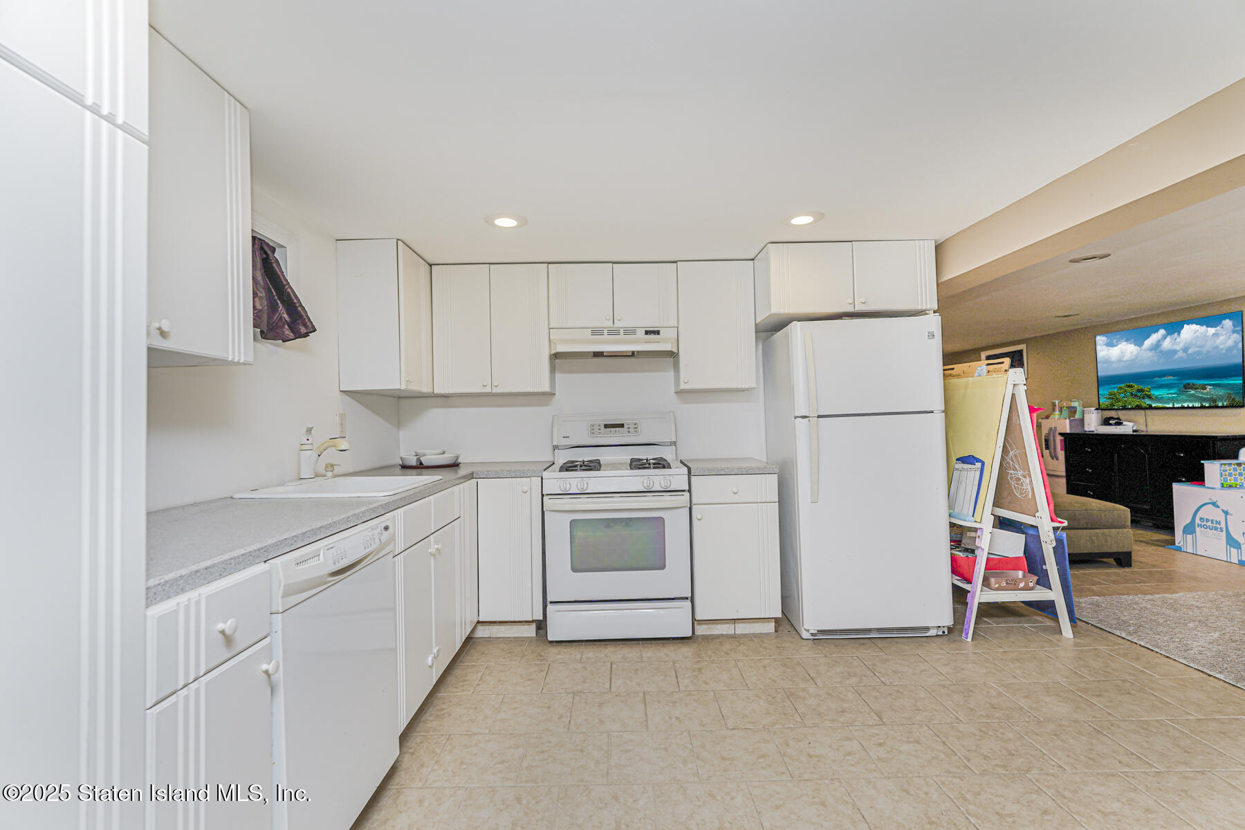 82 Woods Of Arden Road Staten Island, NY 10312 - Photo 22 of 30 a kitchen with a refrigerator a stove and white cabinets