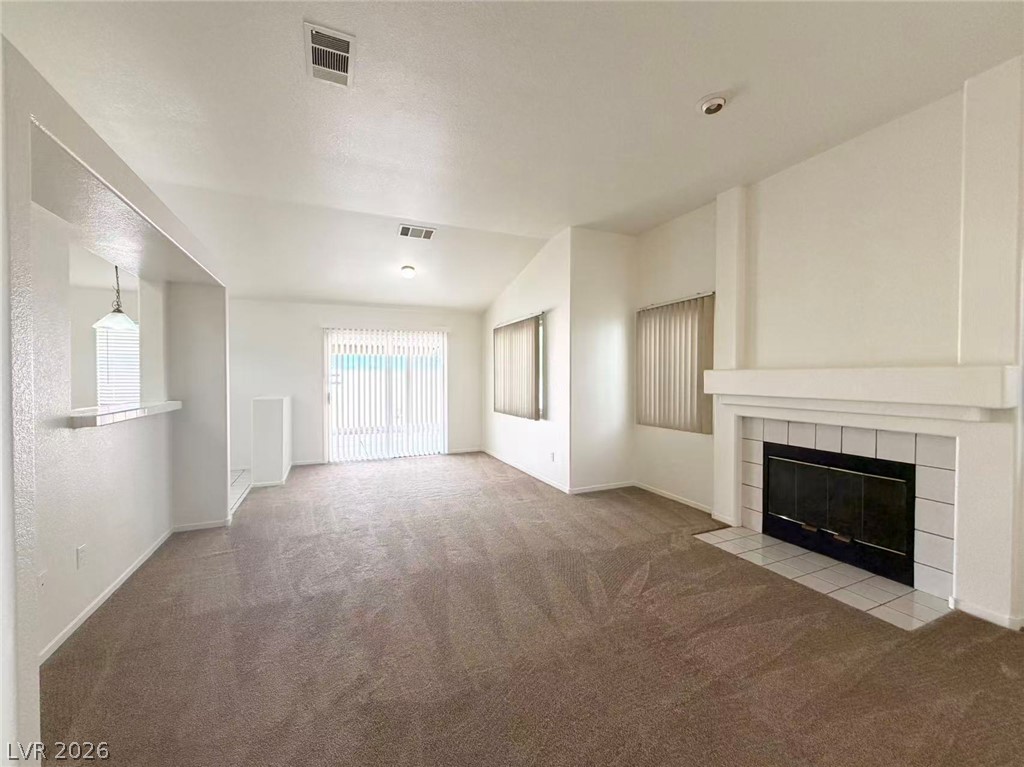 8620 Magnolia Ridge Avenue Las Vegas, NV 89134 - Photo 3 of 15 A spacious common area offers plush carpeted floors, a warm fireplace, and a convenient sliding glass door for outdoor access.