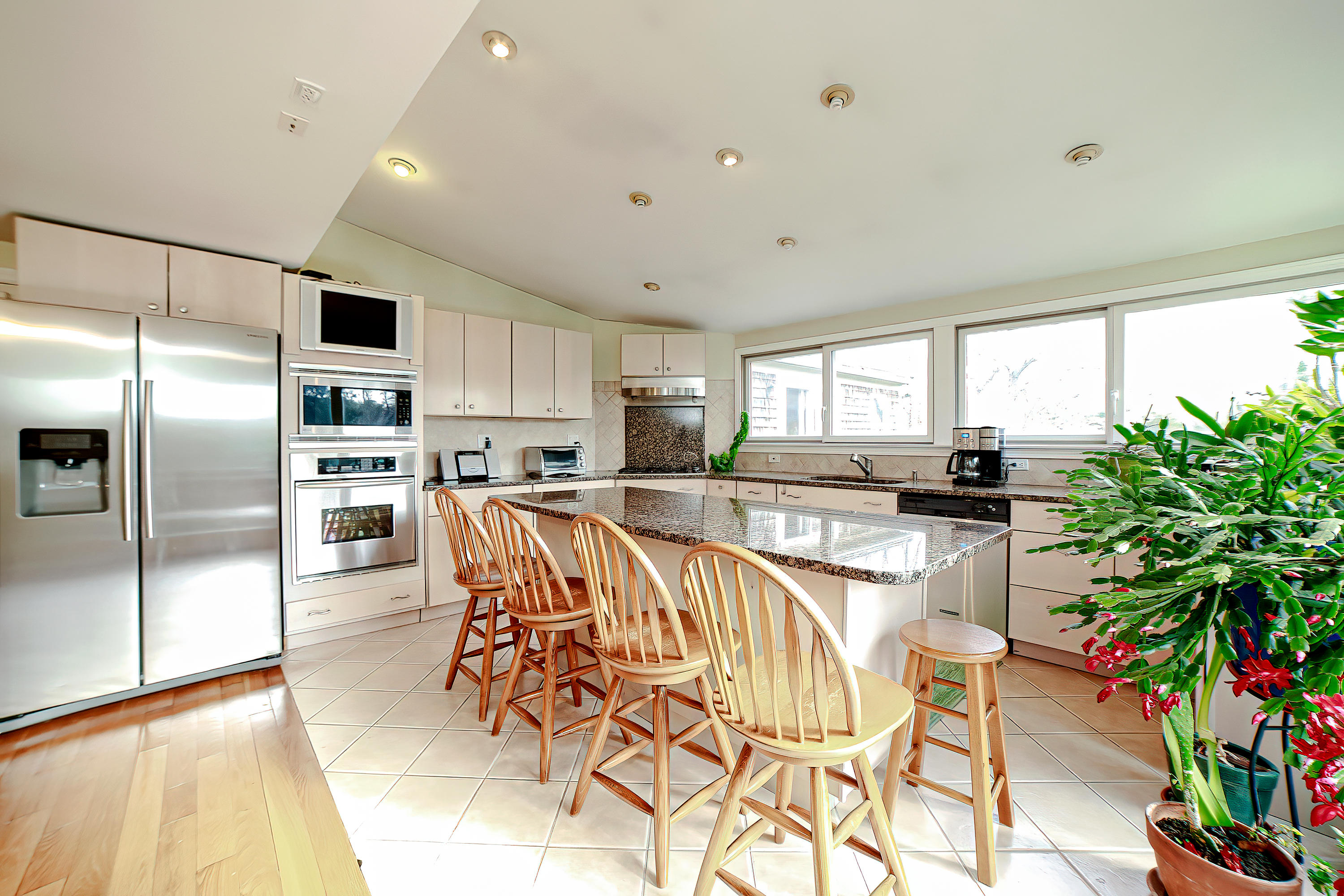 46 Delta Street Hyannis, MA 02601 - Photo 9 of 35 a kitchen with stainless steel appliances kitchen island granite countertop a refrigerator a stove a sink a dining table and chairs with wooden floor