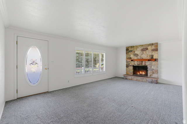 148 Tennyson Avenue Sandy, UT 84070 - Photo 9 of 55 Living area featuring a stone-faced fireplace with a wood mantel, light gray carpeting, and white window shutters