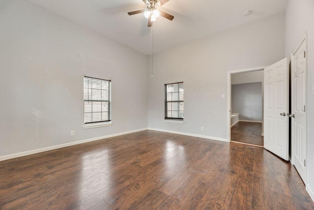 500 East Main Street Denison, TX 75021 - Photo 16 of 21 Unfurnished bedroom with dark wood-type flooring, multiple windows, ceiling fan, and a high ceiling