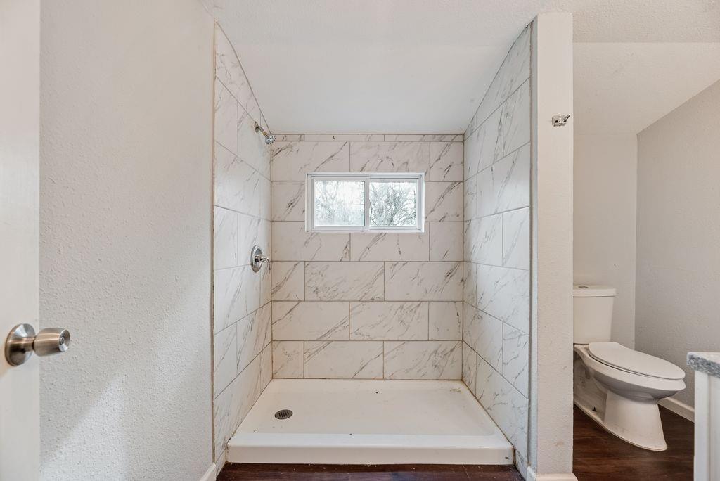 500 East Main Street Denison, TX 75021 - Photo 18 of 21 Bathroom with a stall shower and dark wood-style floors