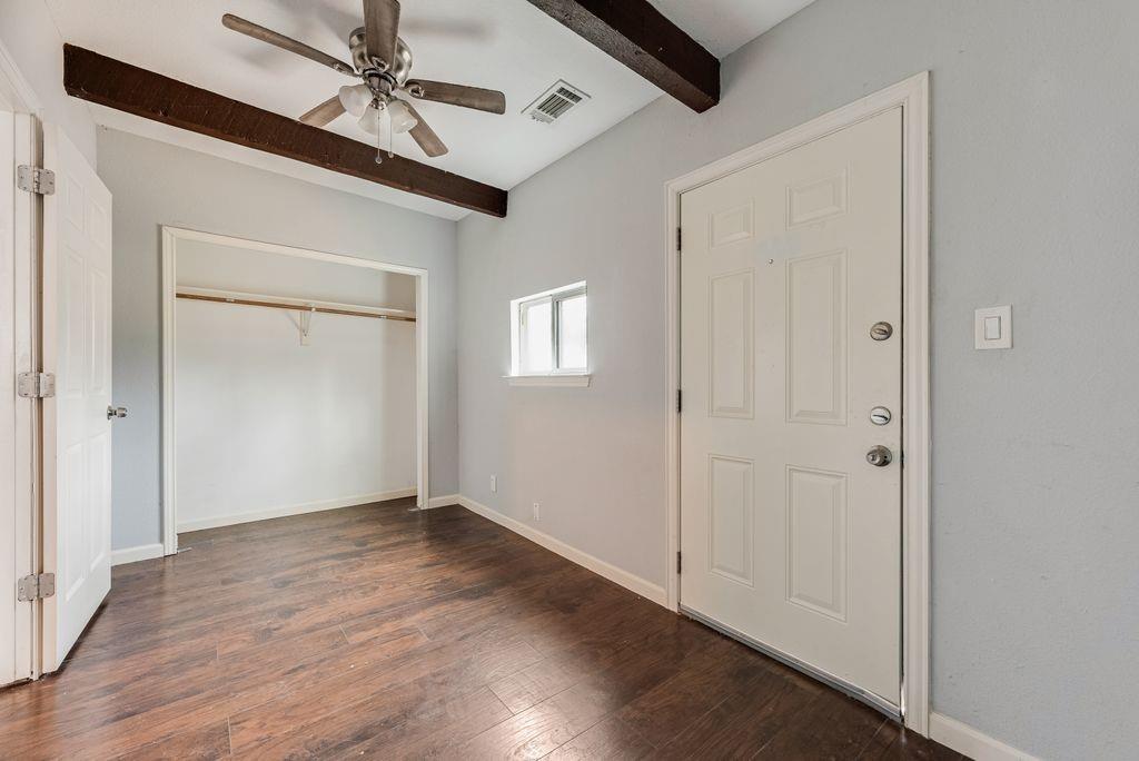 500 East Main Street Denison, TX 75021 - Photo 7 of 21 Unfurnished bedroom featuring dark wood-type flooring, beam ceiling, a ceiling fan, and a closet