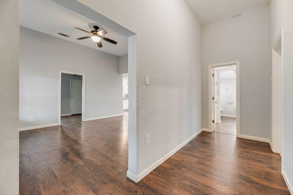500 East Main Street Denison, TX 75021 - Photo 8 of 21 Empty room with dark wood finished floors, ceiling fan, and a high ceiling