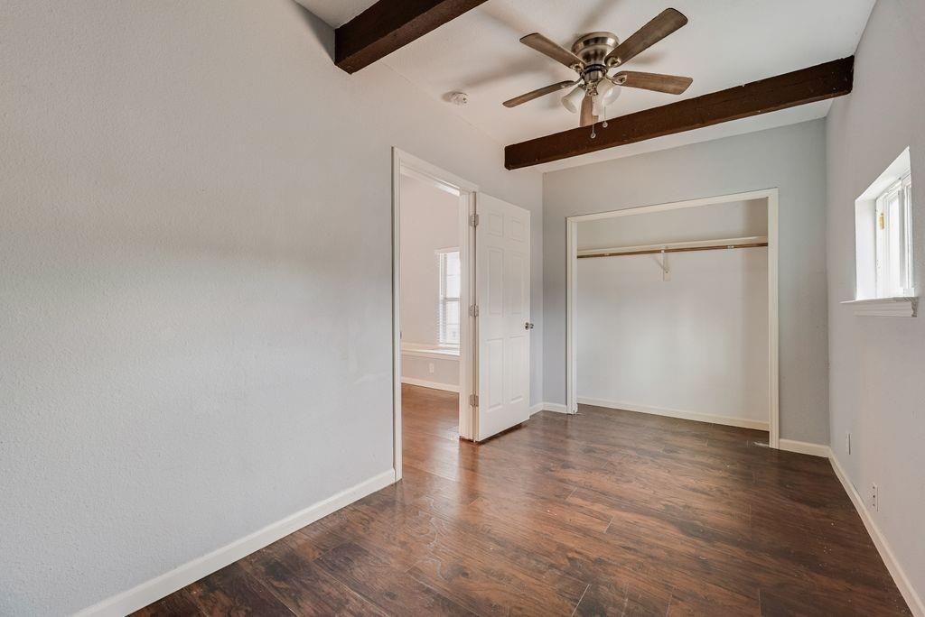 500 East Main Street Denison, TX 75021 - Photo 9 of 21 Unfurnished bedroom with dark wood-style floors, beamed ceiling, a ceiling fan, and a closet