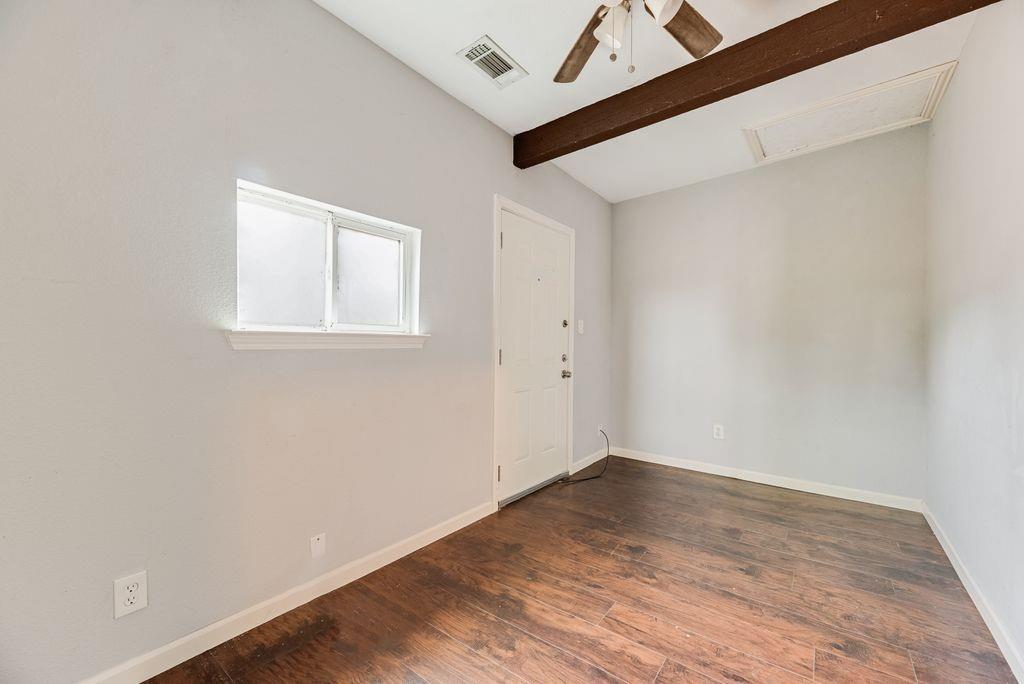500 East Main Street Denison, TX 75021 - Photo 10 of 21 Empty room with a ceiling fan, dark wood finished floors, and vaulted ceiling with beams