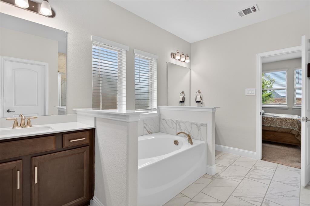 1002 Coppersmith Way Forney, TX 75126 - Photo 19 of 39 a bathroom with a bathtub sink and mirror
