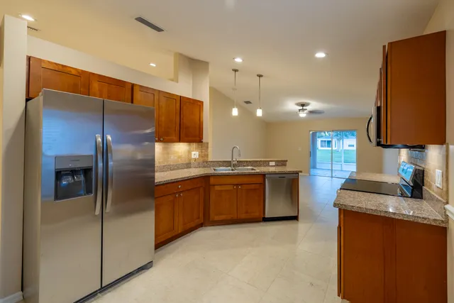 a kitchen with stainless steel appliances granite countertop a refrigerator a sink a stove and oven