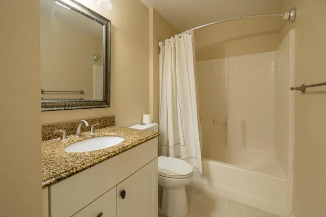 a bathroom with a granite countertop sink toilet and shower