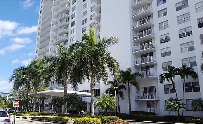 a front view of a multi story building with yard and palm trees