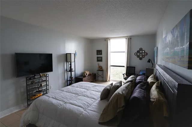 a bedroom with a bed and a flat tv screen on the dresser