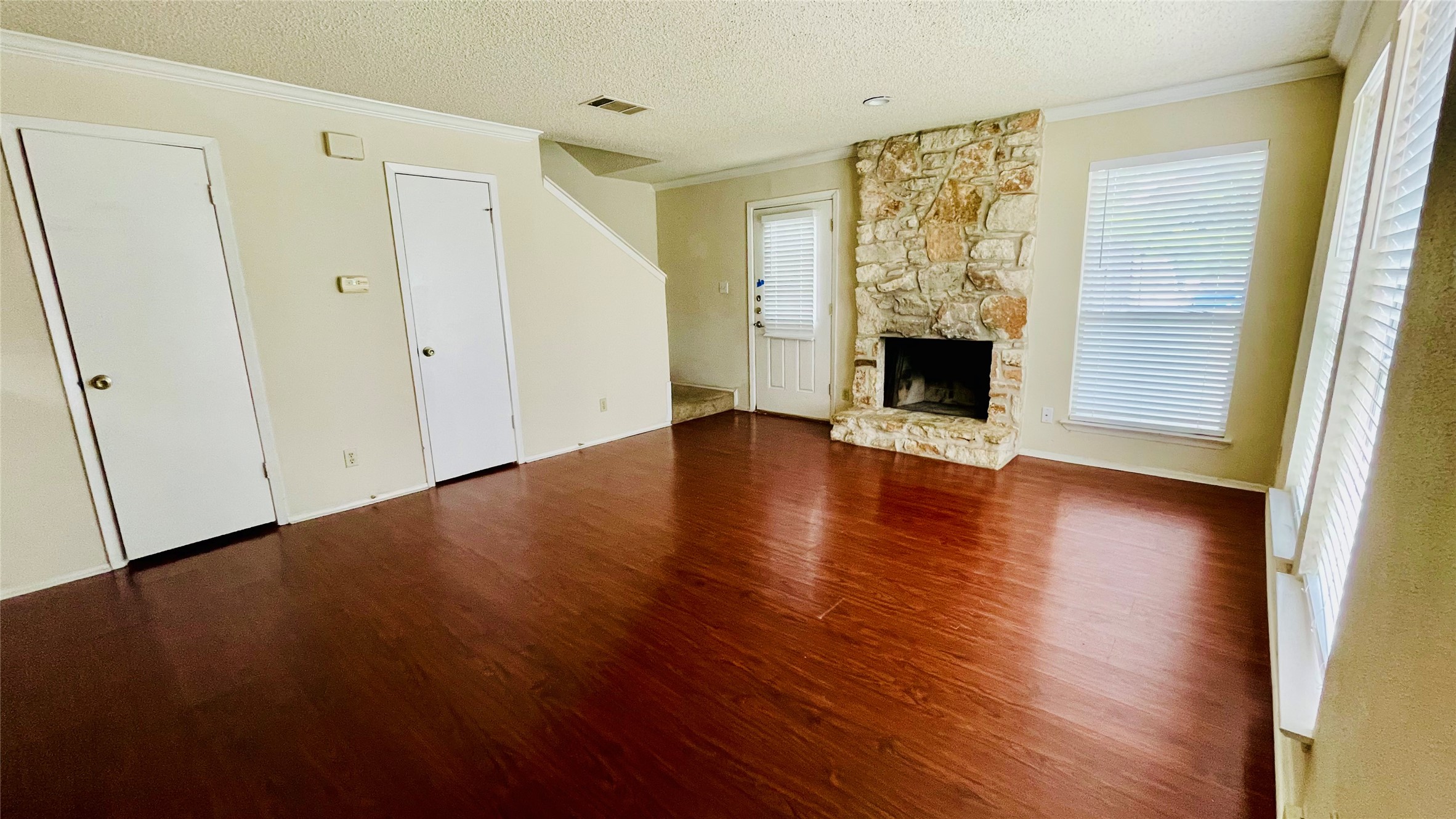 1405 D Camp Craft Road, Unit D West Lake Hills, TX 78746 - Photo 4 of 9 Unfurnished living room featuring a stone fireplace, ornamental molding, a textured ceiling, and dark wood-type flooring