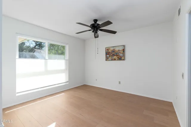 an empty room with a window and a ceiling fan