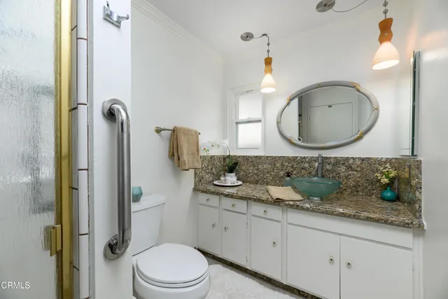 a bathroom with a granite countertop sink mirror vanity and toilet