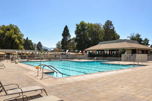 a view of swimming pool with outdoor seating and trees in the background