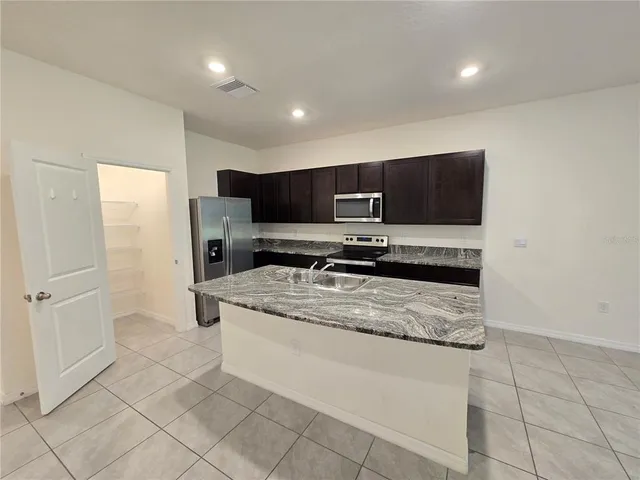 a kitchen with stainless steel appliances a sink a stove a microwave a counter top space and cabinets