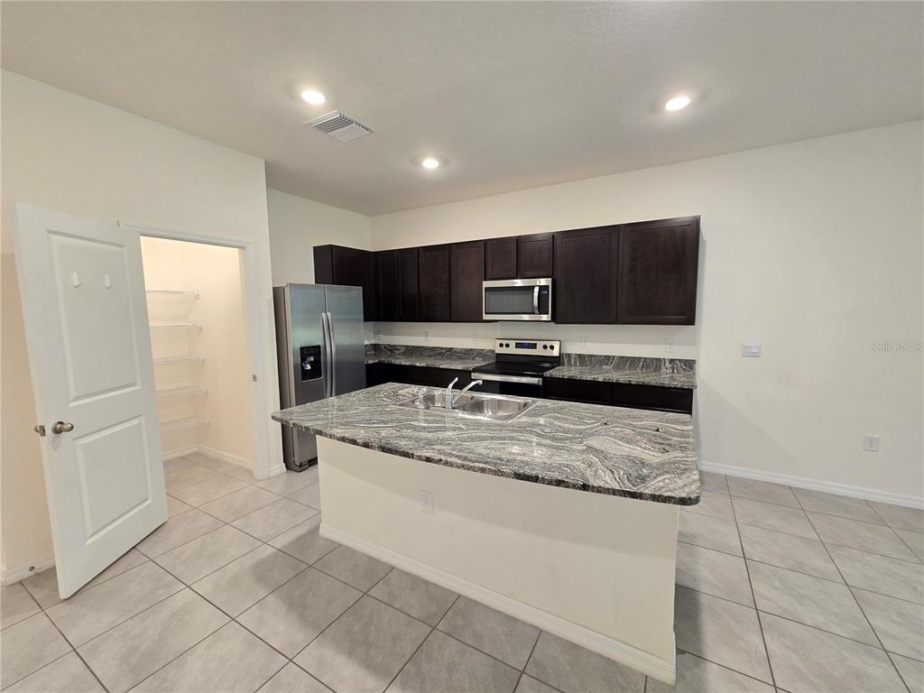 32803 Pez Landing Lane Wesley Chapel, FL 33543 - Photo 4 of 23 a kitchen with stainless steel appliances a sink a stove a microwave a counter top space and cabinets