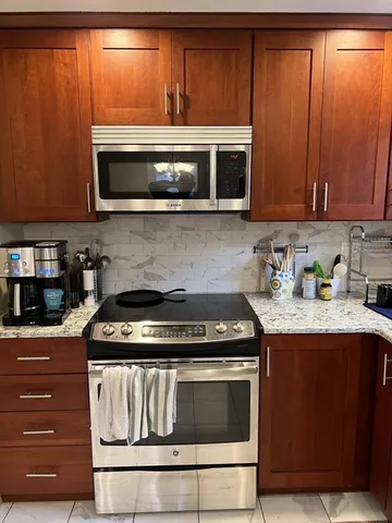 a kitchen with stainless steel appliances granite countertop wooden cabinets and a stove top oven