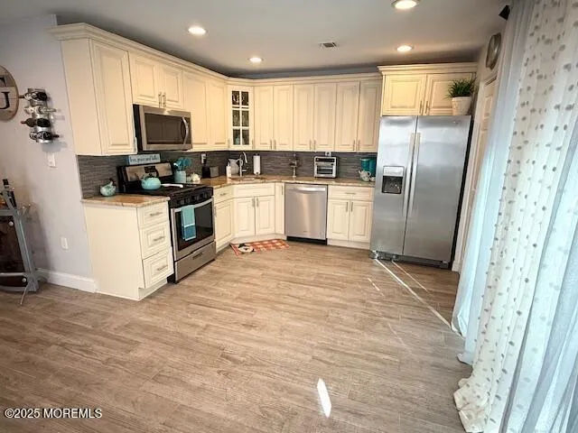 a kitchen with white cabinets stainless steel appliances and a refrigerator
