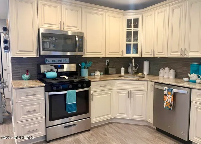 a kitchen with stainless steel appliances granite countertop white cabinets and a stove top oven
