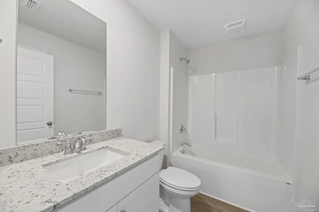 a bathroom with a granite countertop sink a toilet and bathtub