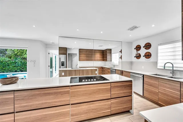 a kitchen with stainless steel appliances kitchen island granite countertop a refrigerator a stove and a sink with wooden floor