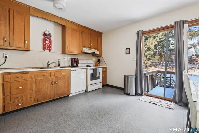 a open kitchen with stainless steel appliances granite countertop a stove a sink and white cabinets with wooden floor