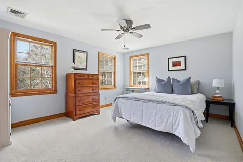 a spacious bedroom with a bed a dresser and a window