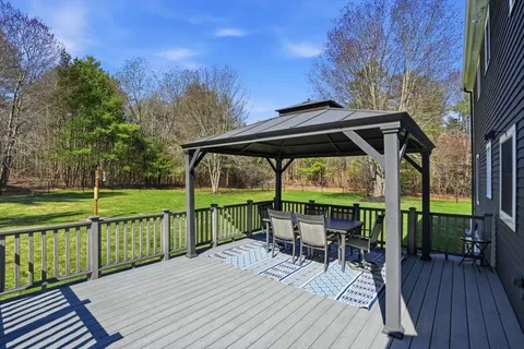 a view of a deck with chairs and wooden floor next to a yard