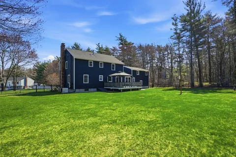 a view of a big house with a big yard and large trees