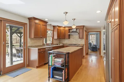 a kitchen with a refrigerator a sink dishwasher a stove and a dining table with wooden floor