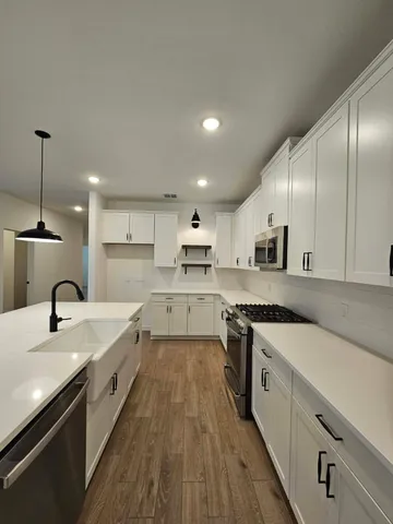 a large kitchen with stainless steel appliances granite countertop a lot of counter space and wooden floors