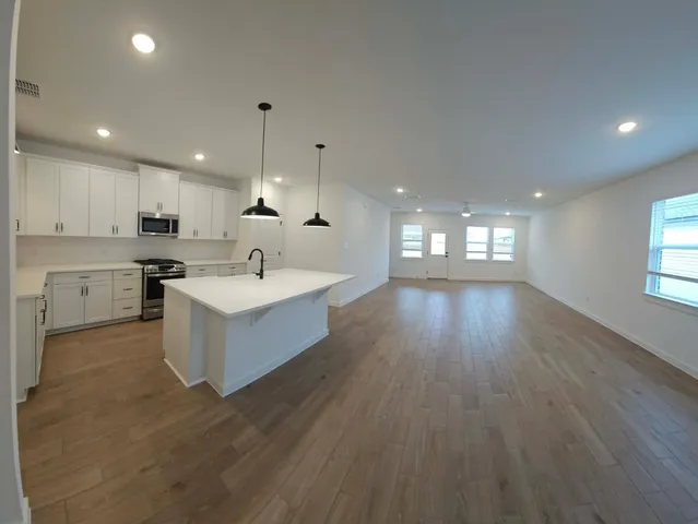 a large room with kitchen island a sink dishwasher a dining table and chairs with wooden floor