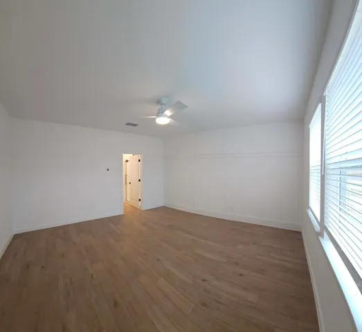 an empty room with wooden floor and windows