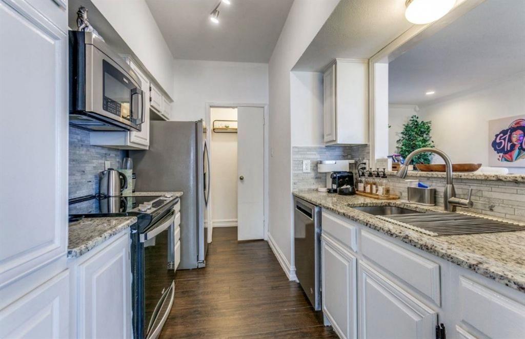 3550 Country Square Drive, Unit 109 Carrollton, TX 75006 - Photo 6 of 13 Kitchen featuring stainless steel appliances, white cabinetry, light stone countertops, decorative backsplash, and dark wood finished floors
