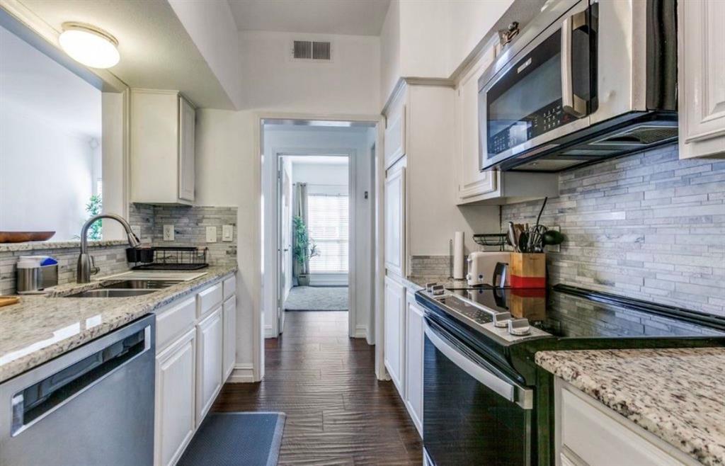 3550 Country Square Drive, Unit 109 Carrollton, TX 75006 - Photo 7 of 13 Kitchen with appliances with stainless steel finishes, decorative backsplash, light stone counters, and white cabinetry