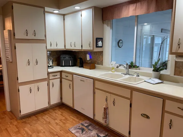 a kitchen with a sink dishwasher and a stove with wooden floor