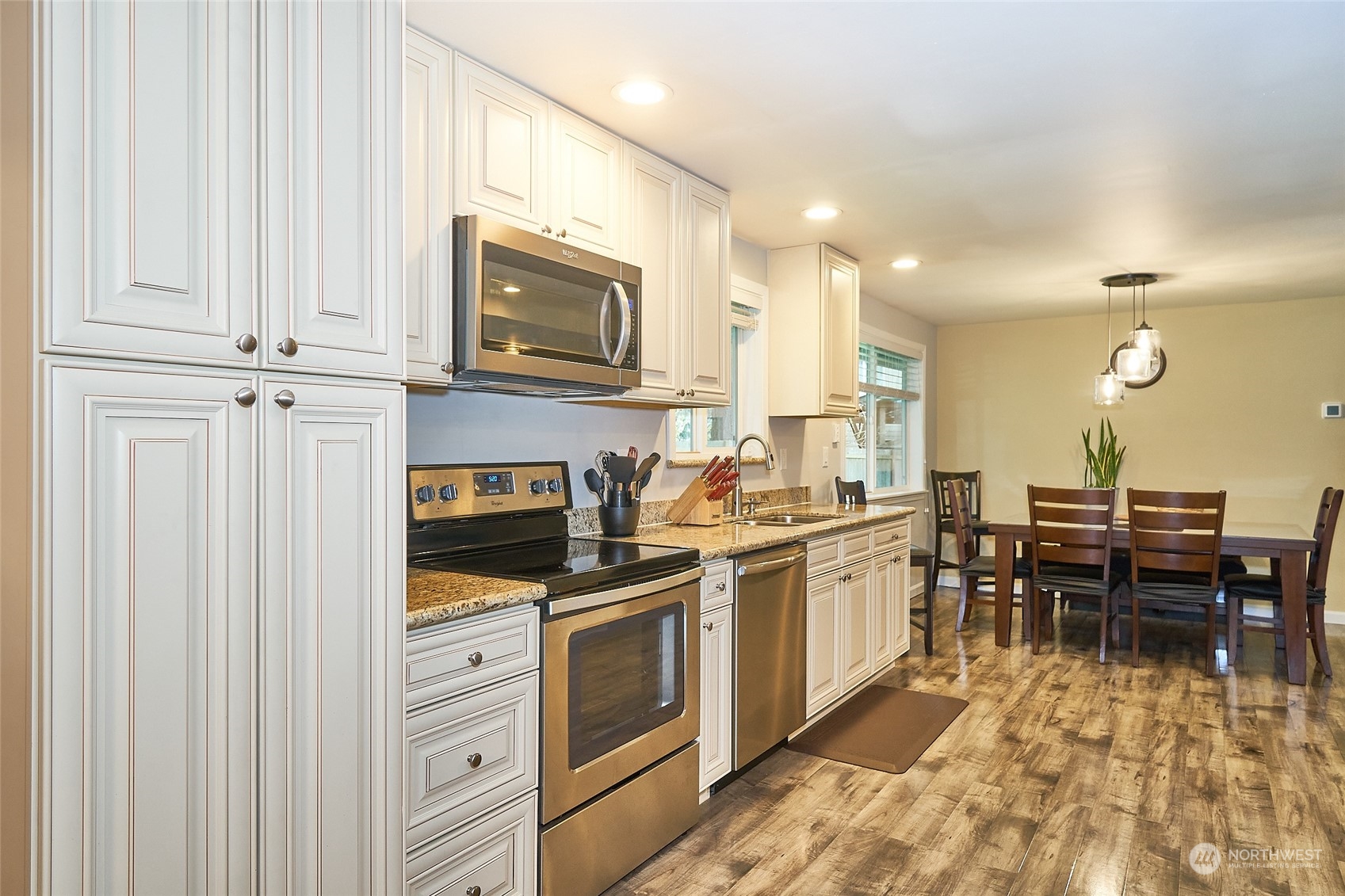 108 183rd Street Southwest Bothell, WA 98012 - Photo 6 of 22 a kitchen with stainless steel appliances granite countertop a stove top oven a sink dishwasher a dining table and chairs with wooden floor