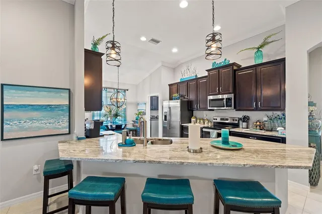 a kitchen with stainless steel appliances kitchen island granite countertop a refrigerator a sink dishwasher a stove and a dining table with wooden floor