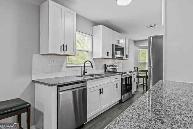 a kitchen with stainless steel appliances granite countertop a sink stove and cabinets