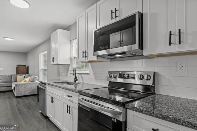 a kitchen with stainless steel appliances granite countertop a sink stove and microwave