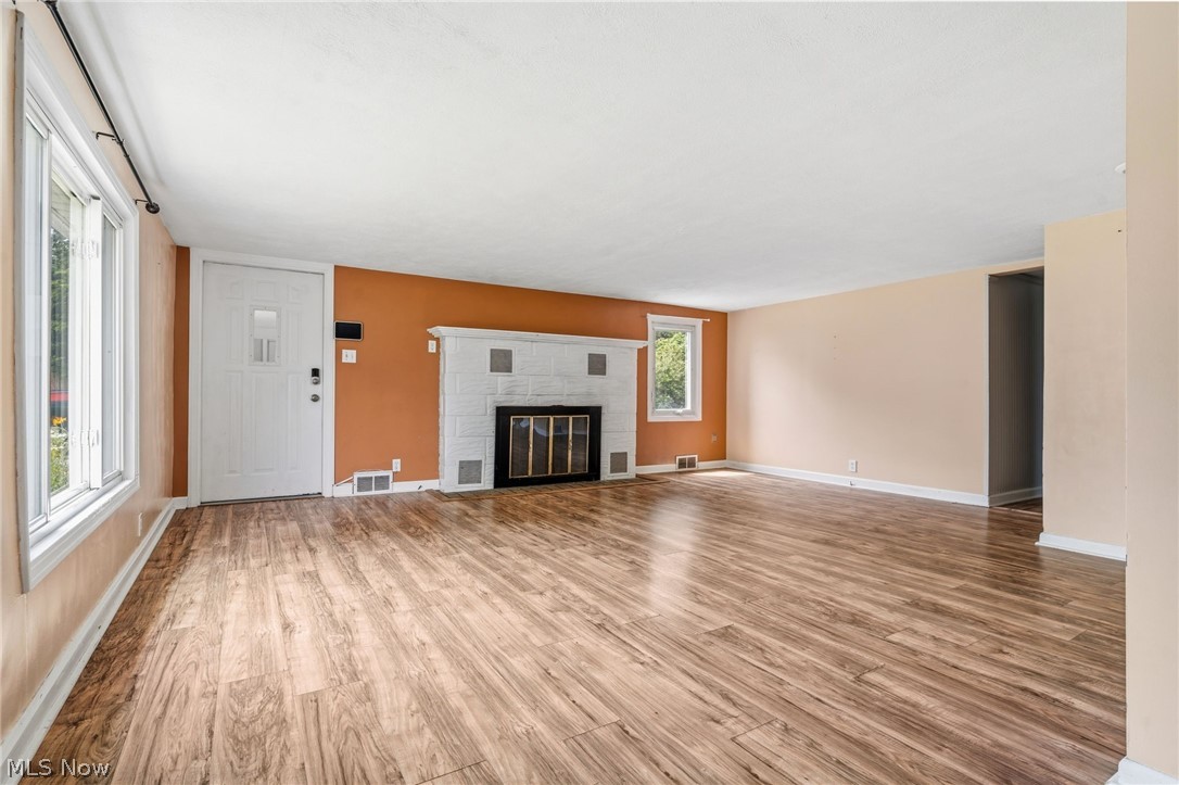 4449 18th Street Northwest Canton, OH 44708 - Photo 6 of 25 Spacious living area featuring wood-finish flooring, a white paneled entry door, and a fireplace with a white brick surround and black firebox