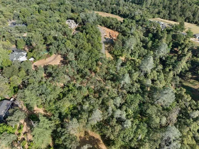 an aerial view of residential houses with outdoor space and trees