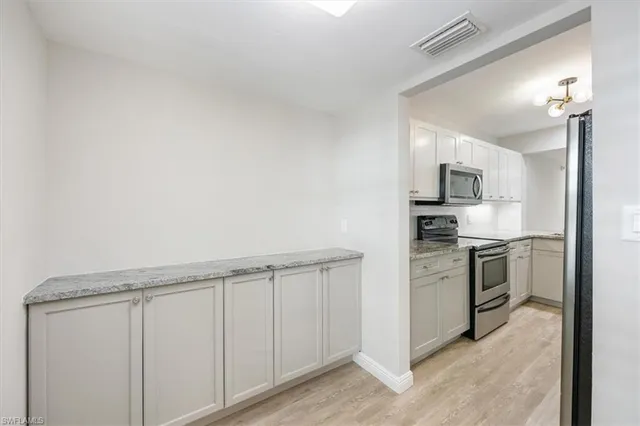 a kitchen with white cabinets and stainless steel appliances