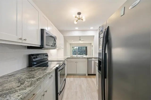 a kitchen with stainless steel appliances granite countertop a refrigerator a stove and a microwave