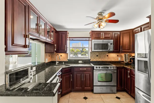 a kitchen with stainless steel appliances granite countertop a stove top oven a refrigerator and a sink with granite countertops