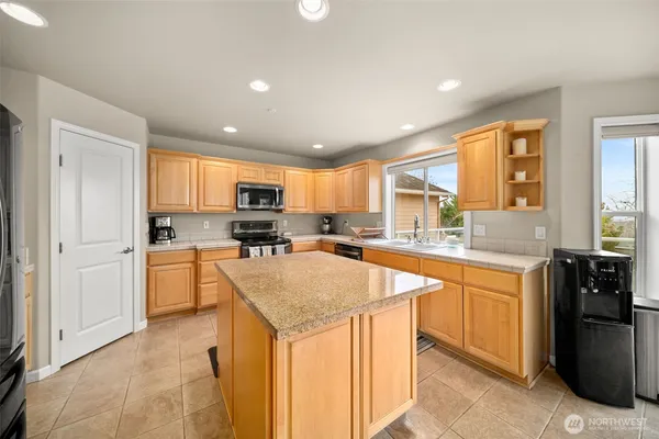 a kitchen with stainless steel appliances granite countertop a refrigerator a sink dishwasher a stove and white countertops with wooden floor